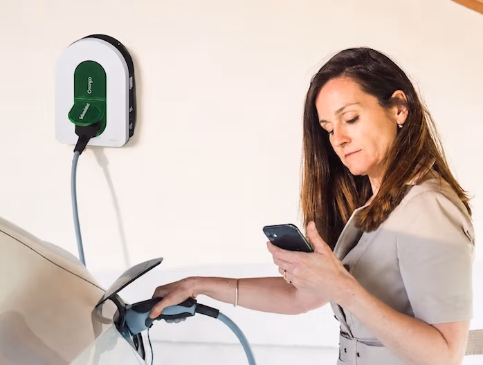 entete particuliers Femme branchant sa voiture électrique sur une borne Schneider Electric installée à domicile par Pro Borne