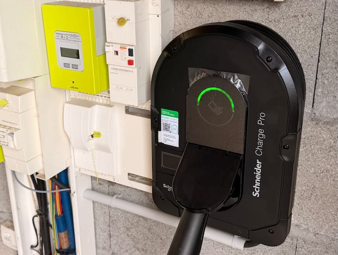 banniere-borne-de-recharge-schneider Femme branchant sa voiture électrique sur une borne Schneider Electric installée à domicile par Pro Borne